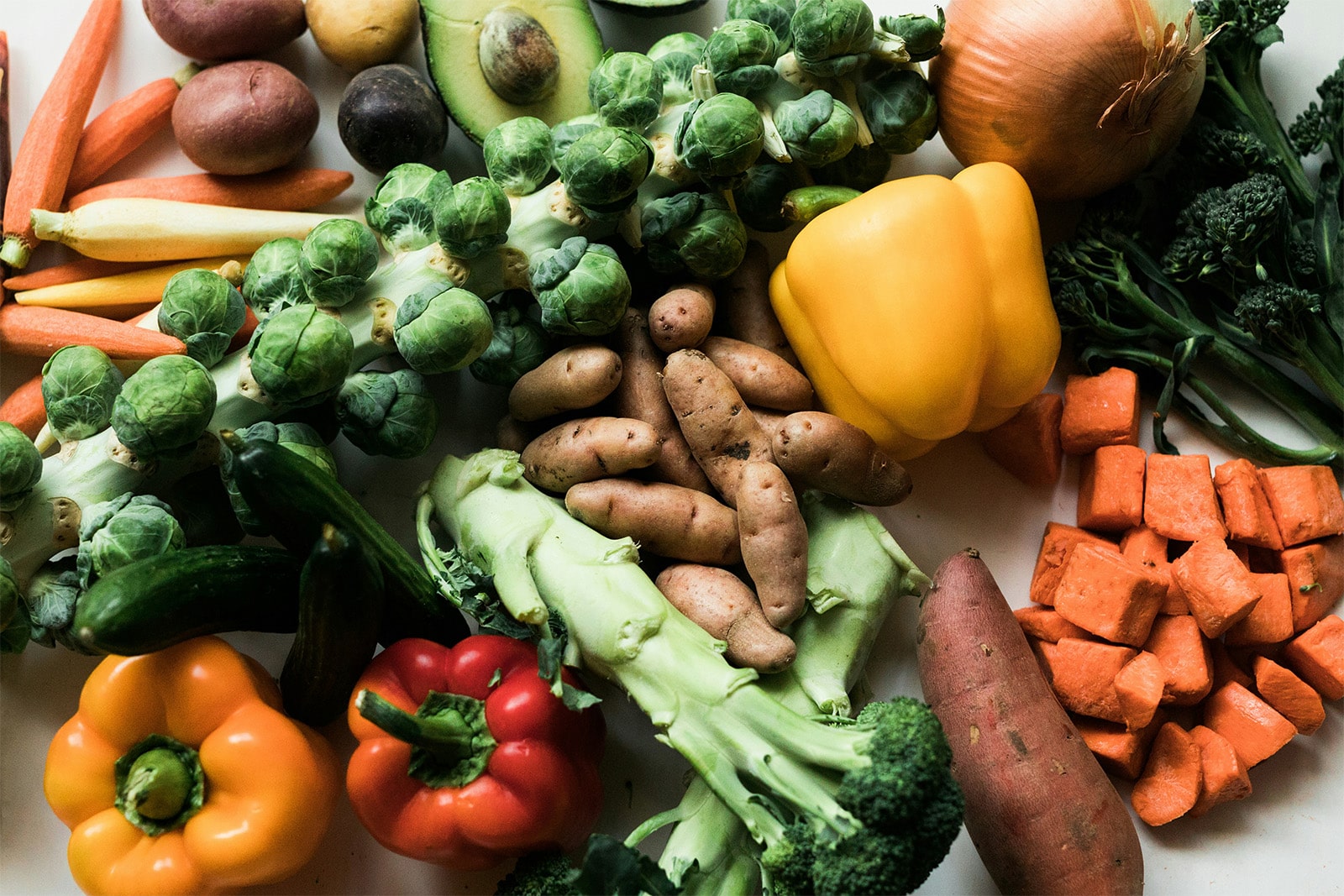 An assortment of fresh vegetables arranged neatly on a white background, highlighting their natural colors and shapes.