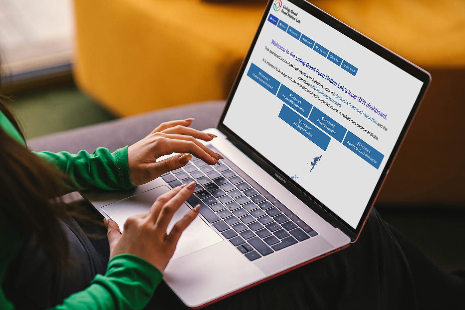 A person seated with a laptop, interacting with the Local Good Food Nation Dashboard