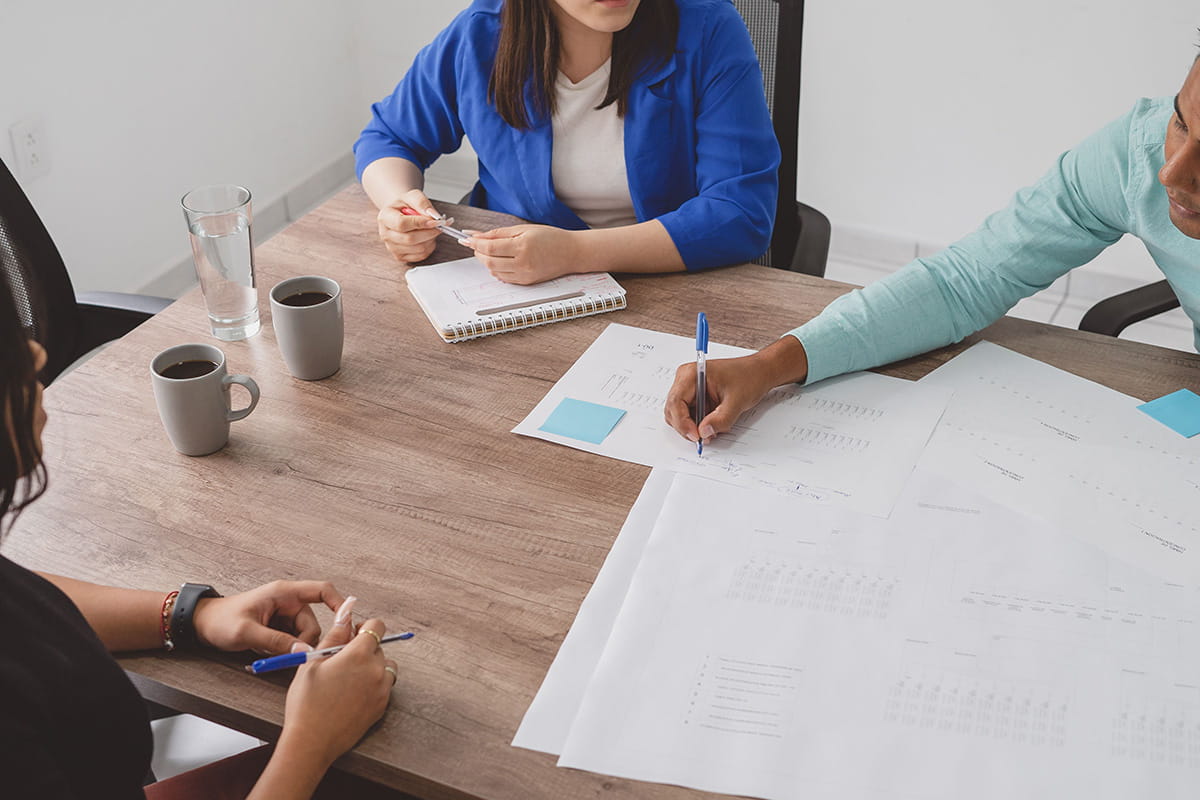 Three people gathered around a table working on paperwork together