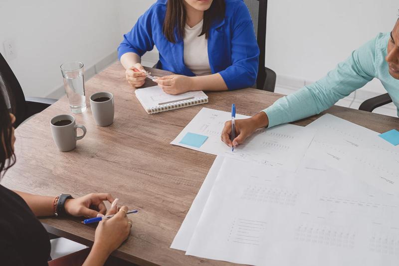 Three people gathered around a table working on paperwork together